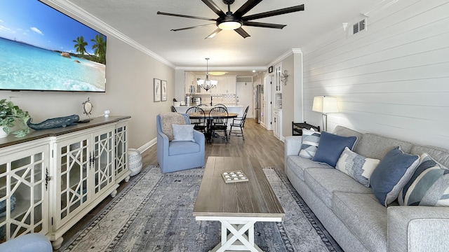 living room with ceiling fan with notable chandelier, hardwood / wood-style flooring, and crown molding