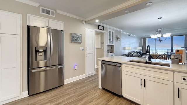 kitchen featuring a chandelier, stainless steel appliances, white cabinetry, and sink