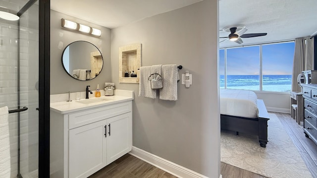 bathroom with hardwood / wood-style flooring, ceiling fan, a water view, and vanity