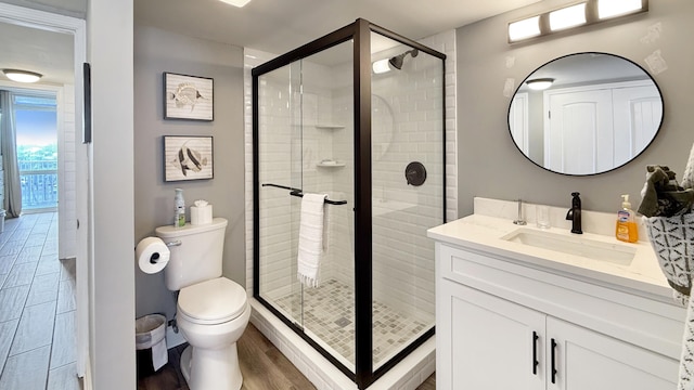 bathroom with vanity, toilet, an enclosed shower, and wood-type flooring