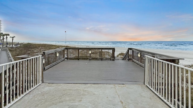 view of dock with a deck with water view and a view of the beach