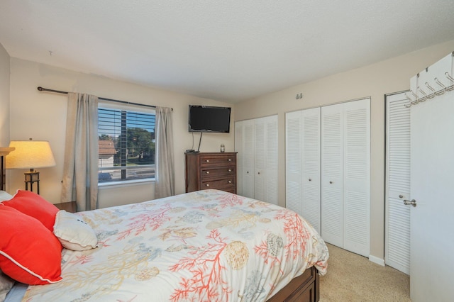 bedroom featuring light carpet and two closets