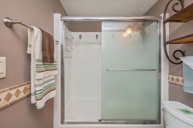 bathroom with toilet, an enclosed shower, and a textured ceiling