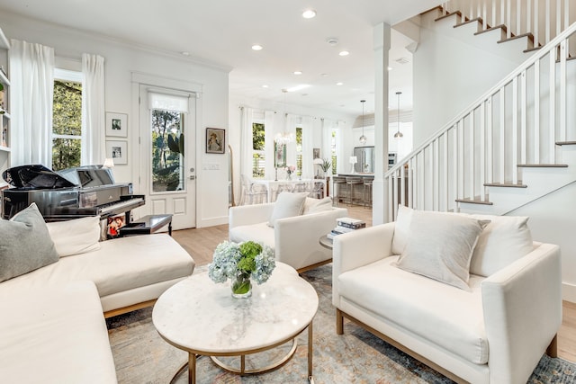 living room featuring light hardwood / wood-style flooring, a wealth of natural light, and crown molding