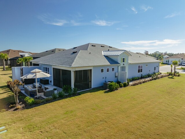 rear view of house with an outdoor living space, a yard, and a sunroom