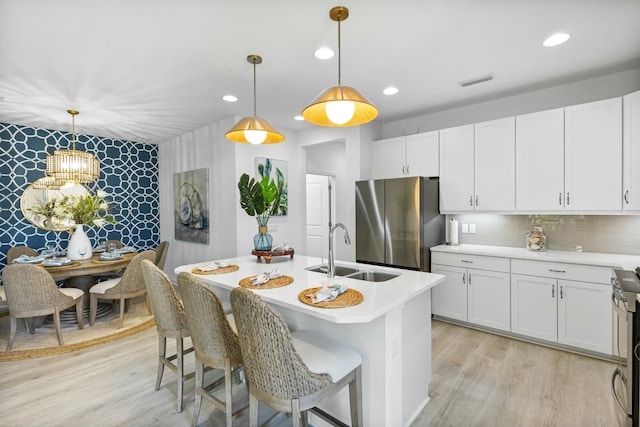 kitchen with white cabinets, stainless steel appliances, hanging light fixtures, and sink