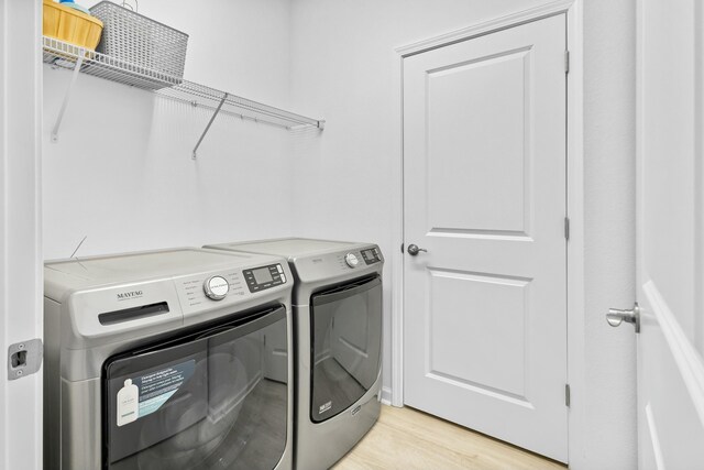 laundry area with independent washer and dryer and light hardwood / wood-style floors