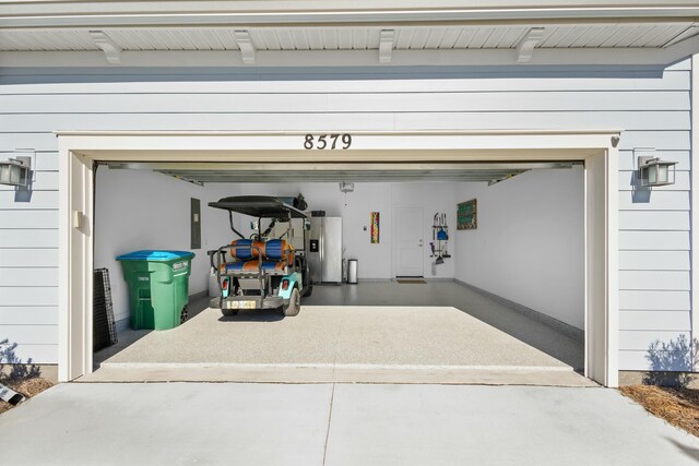 garage featuring electric panel and stainless steel fridge with ice dispenser