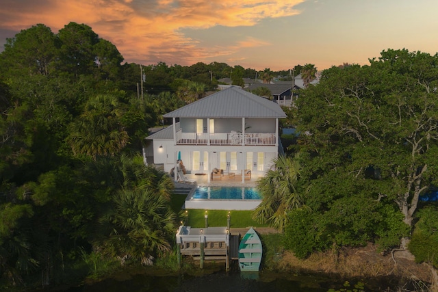 back of property featuring a patio area, an outdoor pool, metal roof, and a balcony