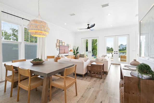 dining space with crown molding, a wealth of natural light, french doors, and light wood finished floors