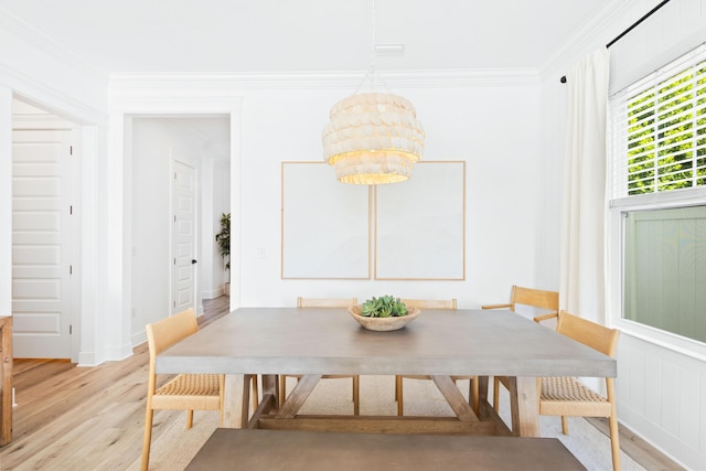 dining area featuring light wood-style floors and crown molding