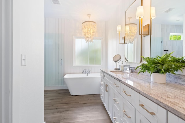 full bathroom featuring vanity, a freestanding tub, wood finished floors, and visible vents