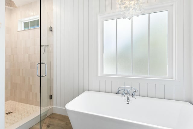 bathroom with a soaking tub, a shower stall, and wood finished floors