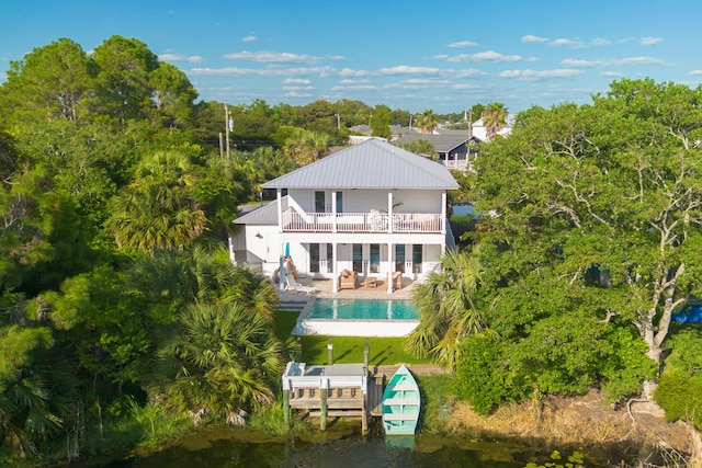 back of house with an outdoor pool, metal roof, a patio, and a balcony