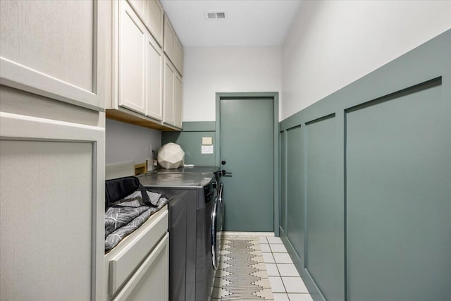 laundry room with cabinets, light tile patterned flooring, and washing machine and dryer