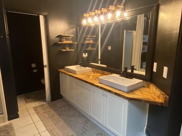 bathroom with toilet, vanity, and tile patterned floors