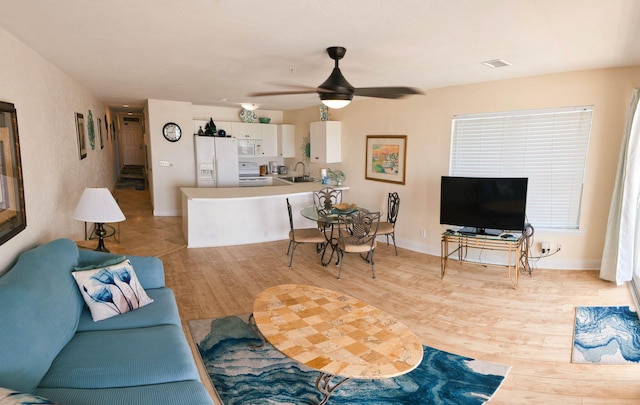 living room featuring ceiling fan, light hardwood / wood-style flooring, and sink