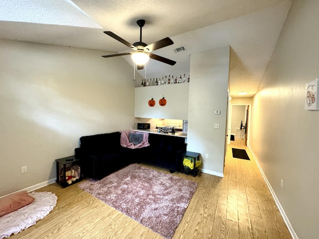 interior space with ceiling fan, light wood-type flooring, a textured ceiling, and vaulted ceiling