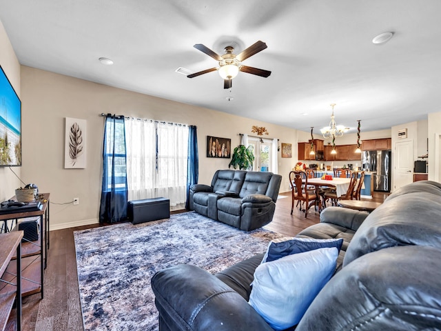 living room with dark hardwood / wood-style floors and ceiling fan with notable chandelier