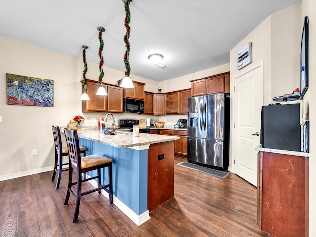 kitchen featuring kitchen peninsula, light stone counters, dark wood-type flooring, and black appliances