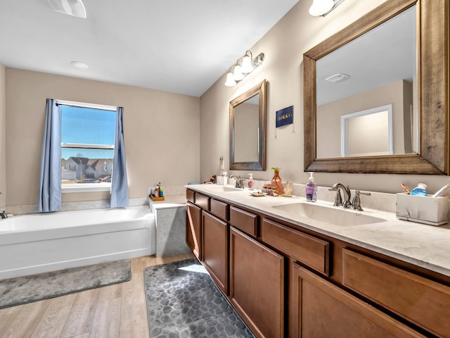 bathroom with a tub to relax in, vanity, and hardwood / wood-style flooring