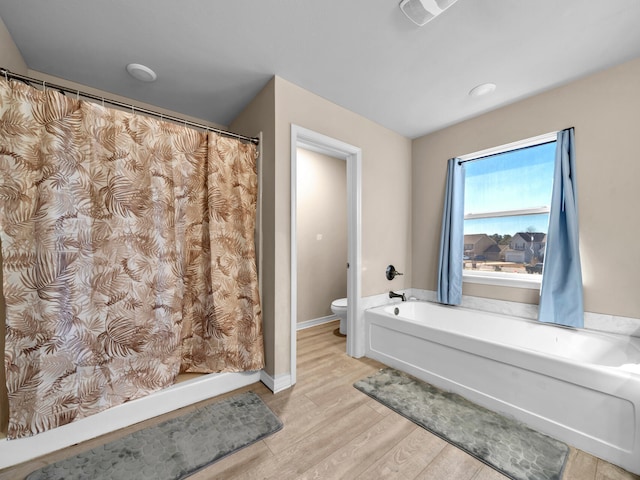 bathroom with hardwood / wood-style floors, toilet, and a bath