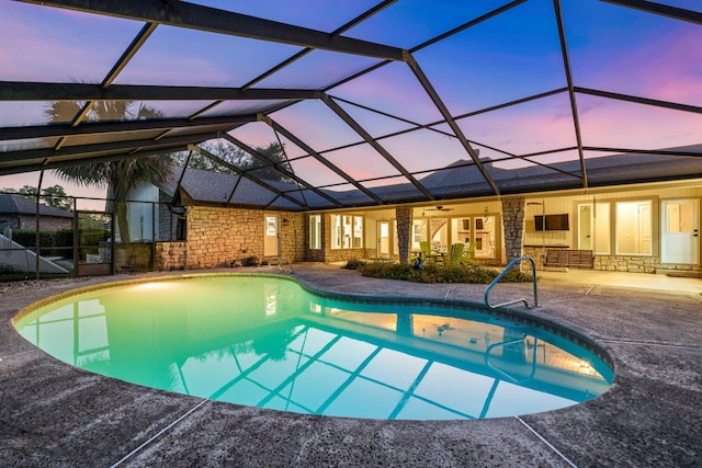 pool at dusk featuring glass enclosure and a patio area