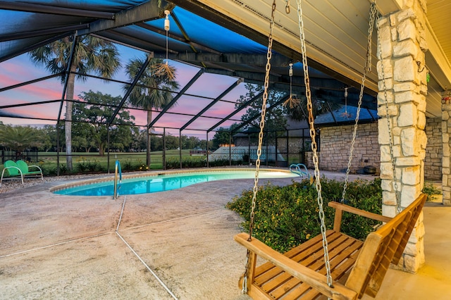 pool at dusk featuring a lanai and a patio