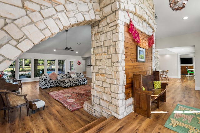 living room with vaulted ceiling, ceiling fan, wood-type flooring, and wood walls