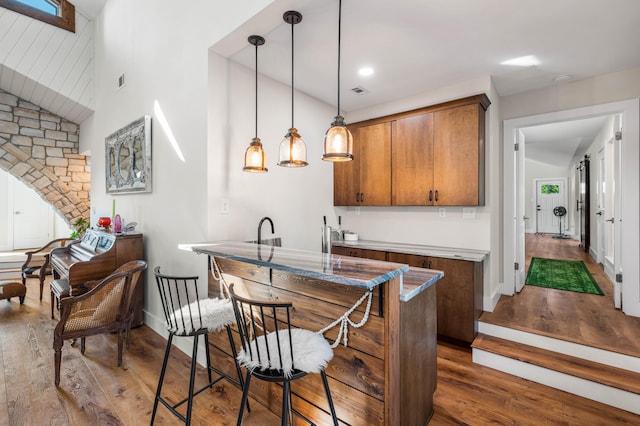 kitchen featuring vaulted ceiling, dark wood-type flooring, pendant lighting, and sink