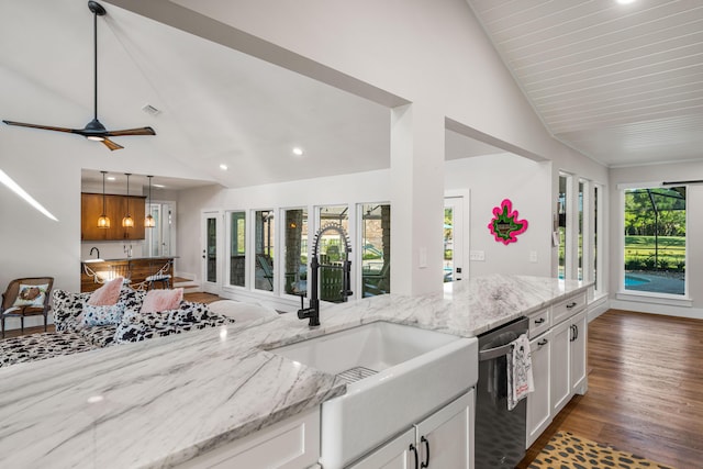 kitchen with vaulted ceiling, dishwasher, sink, white cabinetry, and light stone counters