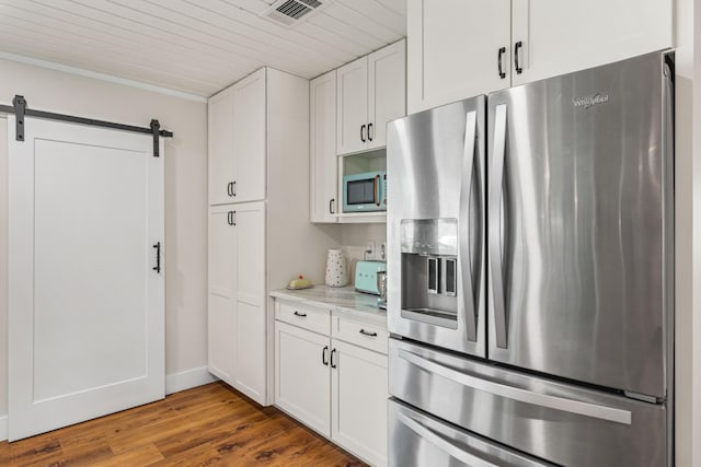 kitchen featuring light stone counters, white cabinetry, stainless steel appliances, and a barn door