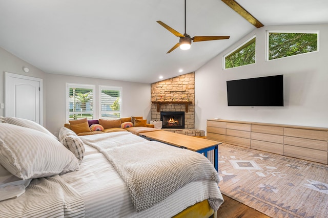 bedroom featuring ceiling fan, vaulted ceiling with beams, wood-type flooring, and a fireplace