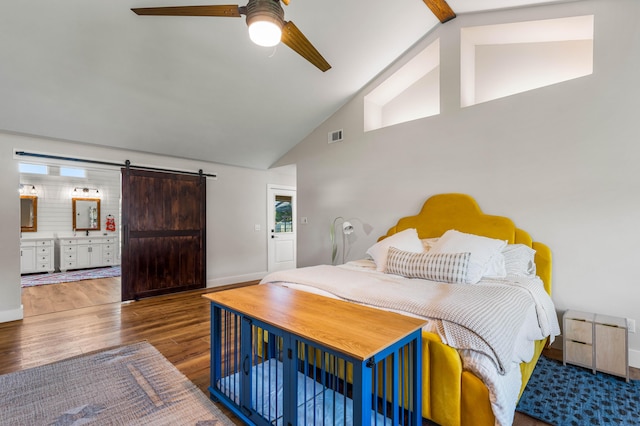 bedroom featuring ceiling fan, a barn door, multiple windows, and hardwood / wood-style flooring