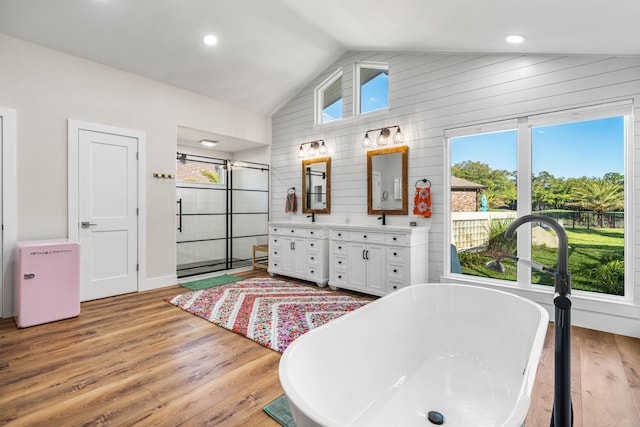 bathroom with lofted ceiling, vanity, a bathtub, and hardwood / wood-style flooring