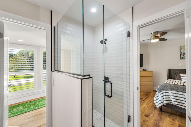 bathroom featuring ceiling fan, wood-type flooring, and a shower with door