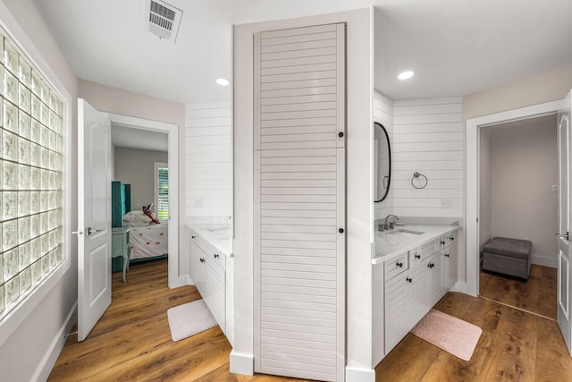 bathroom featuring hardwood / wood-style flooring, vanity, and wooden walls