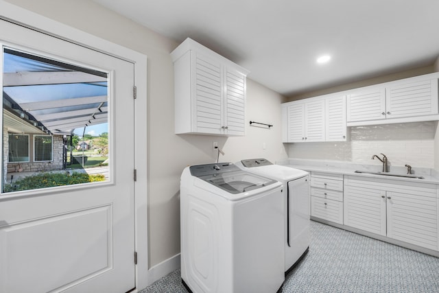 clothes washing area featuring washing machine and dryer, sink, and cabinets