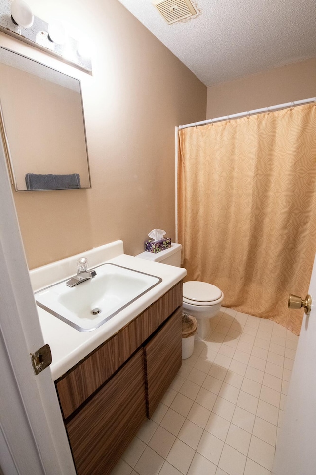 bathroom with toilet, a textured ceiling, vanity, and tile patterned floors