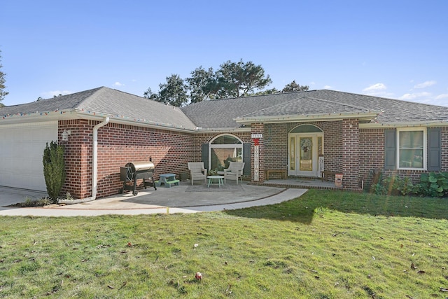 rear view of property featuring a yard, a patio, and a garage