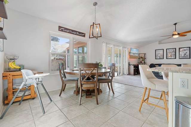 dining room featuring ceiling fan with notable chandelier, light tile patterned flooring, and vaulted ceiling