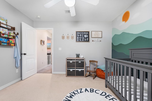 bedroom with light colored carpet, a nursery area, and ceiling fan