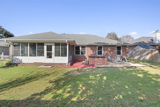 rear view of property with a sunroom, a yard, a patio, and a hot tub