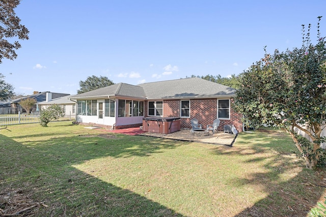 back of house featuring a patio, a yard, a hot tub, and a sunroom