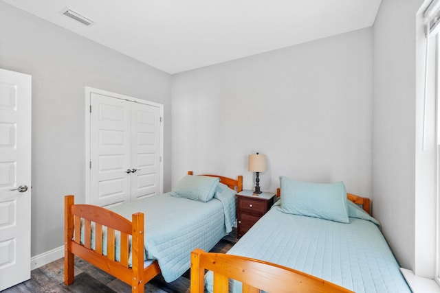 bedroom with dark hardwood / wood-style floors and a closet