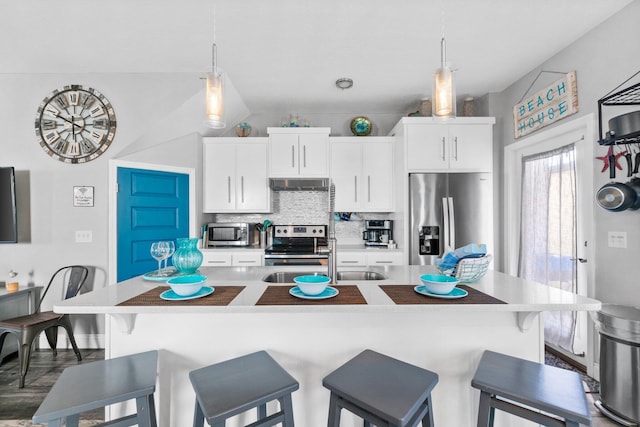 kitchen with white cabinets, stainless steel appliances, a center island with sink, and a breakfast bar area