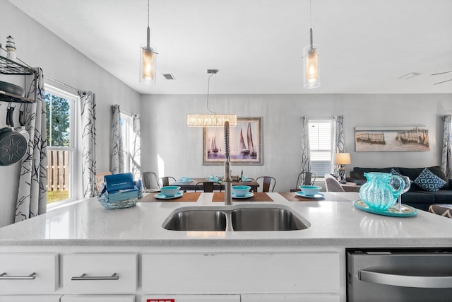 kitchen with dishwasher, sink, decorative light fixtures, white cabinetry, and a chandelier