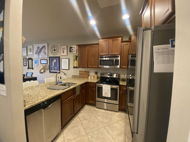 kitchen with sink, decorative backsplash, light stone counters, kitchen peninsula, and stainless steel appliances