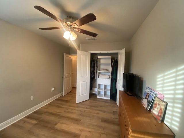 unfurnished bedroom with ceiling fan, a closet, and hardwood / wood-style flooring