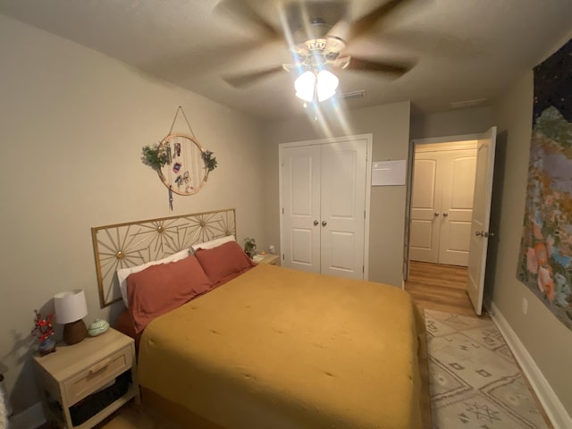 bedroom with ceiling fan, light hardwood / wood-style floors, and a closet